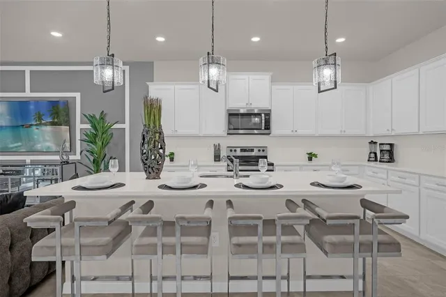 a kitchen with stainless steel appliances kitchen island granite countertop a dining table chairs and white cabinets