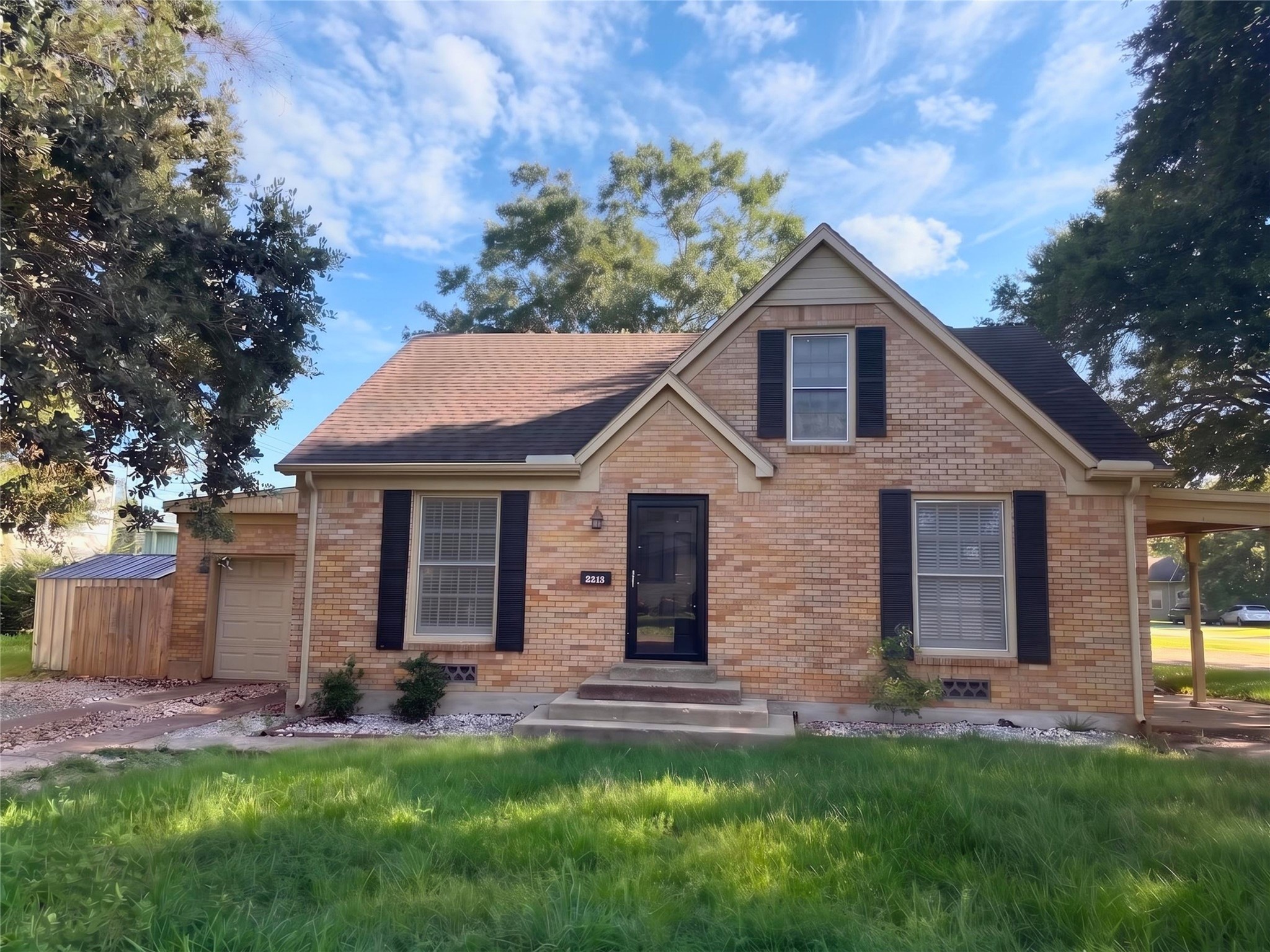 2313 Avenue L Rosenberg, TX 77471 - Photo 29 of 31 Front elevation showcasing classic brick exterior, mature shade trees, and spacious corner lot.