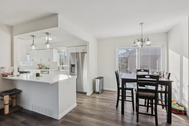 a view of a dining room and livingroom with furniture wooden floor a chandelier