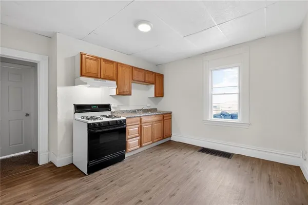 a kitchen with granite countertop a stove and a wooden floors