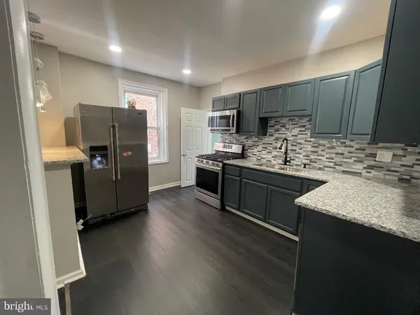 a kitchen with stainless steel appliances kitchen island granite countertop a refrigerator stove and sink