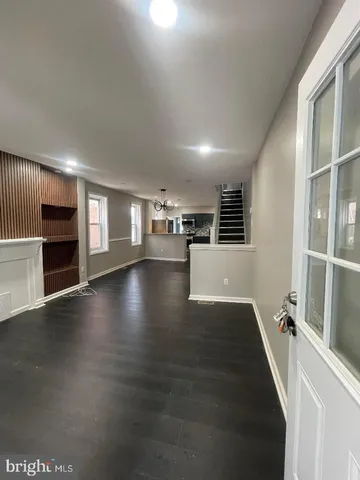 an empty room with wooden floor and a kitchen