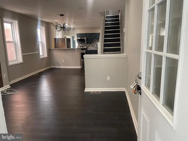 an empty room with wooden floor and a kitchen