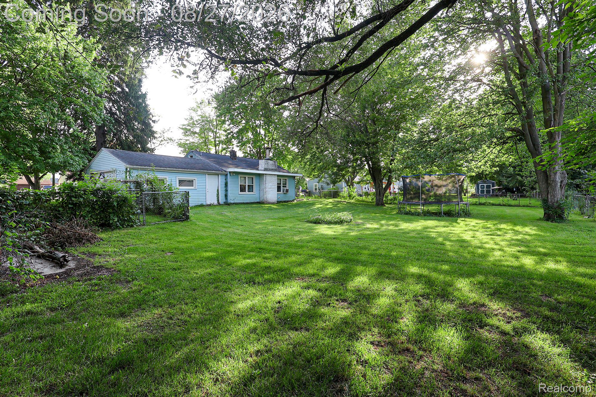 Expansive rear yard featuring mature trees and a chain-link fence