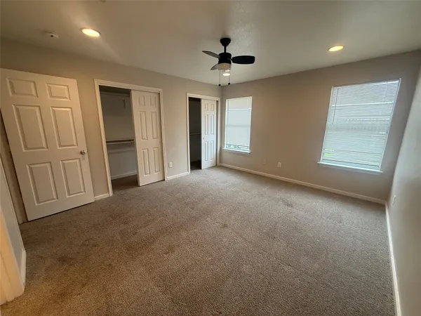 an empty room with windows and fan