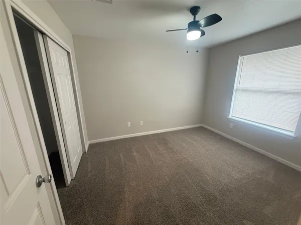 an empty room with a ceiling fan and windows