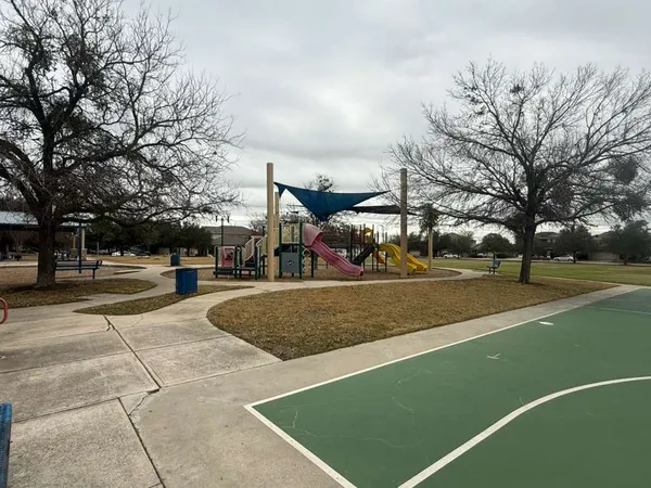 a view of a tennis ground with large trees