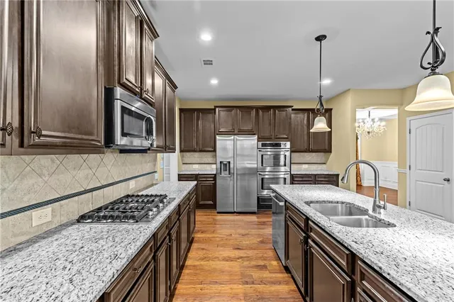 a kitchen with stainless steel appliances granite countertop a stove and a wooden floors