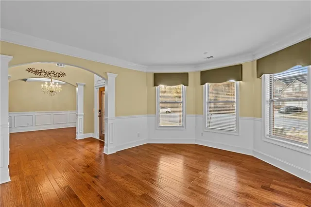 a view of an empty room with window and wooden floor