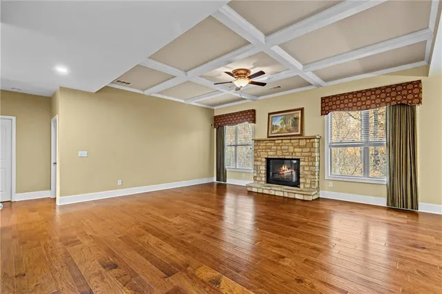 a view of a livingroom with a fireplace a ceiling fan and wooden floor