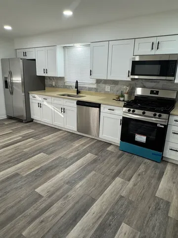 a kitchen with stainless steel appliances granite countertop a stove a sink and a microwave