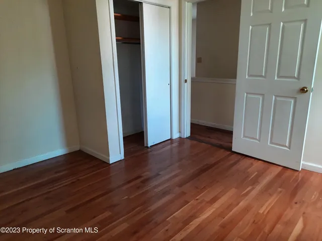 a view of an empty room with wooden floor and closet