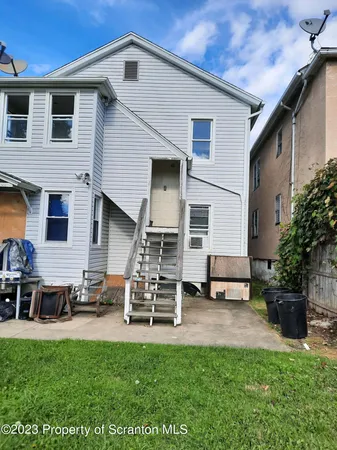a view of a white house with a table and chairs in patio