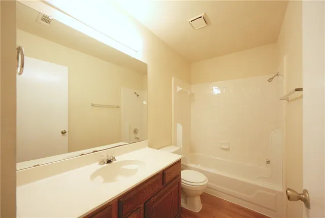 a bathroom with a granite countertop toilet sink and mirror