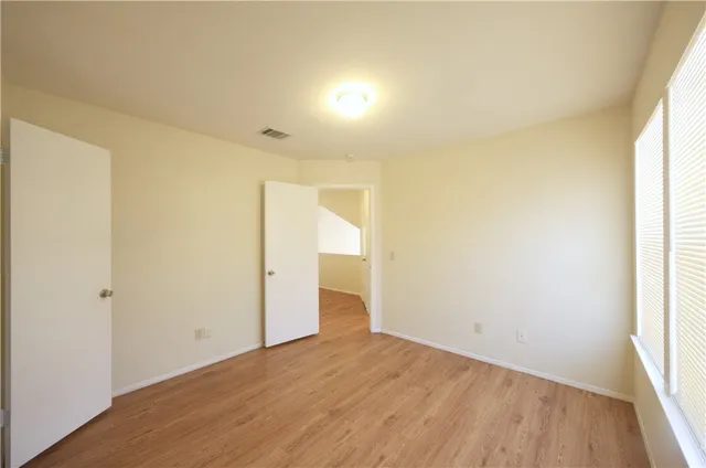 an empty room with wooden floor and windows