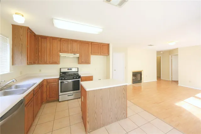 a kitchen with granite countertop a stove a sink and a refrigerator