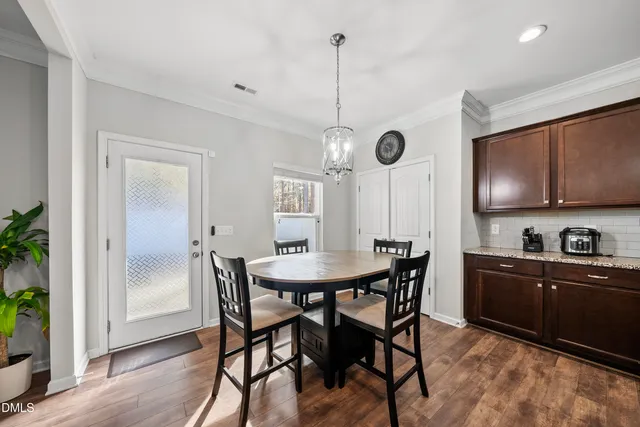 a kitchen with stainless steel appliances granite countertop a dining table chairs and white cabinets
