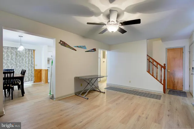a view of a livingroom with a fireplace a chandelier fan and wooden floor