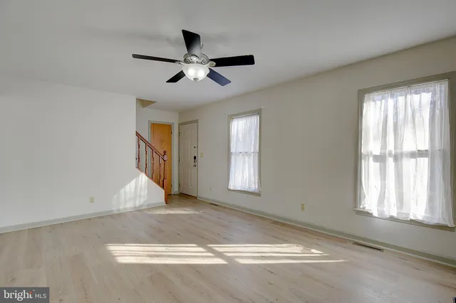 a view of a livingroom with wooden floor and a ceiling fan