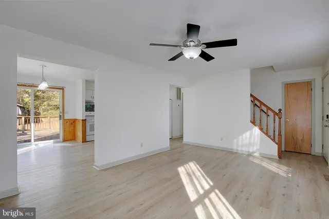 a kitchen with stainless steel appliances granite countertop a refrigerator a stove a sink and white cabinets with wooden floor