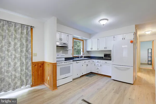 a kitchen with white cabinets and wooden floor