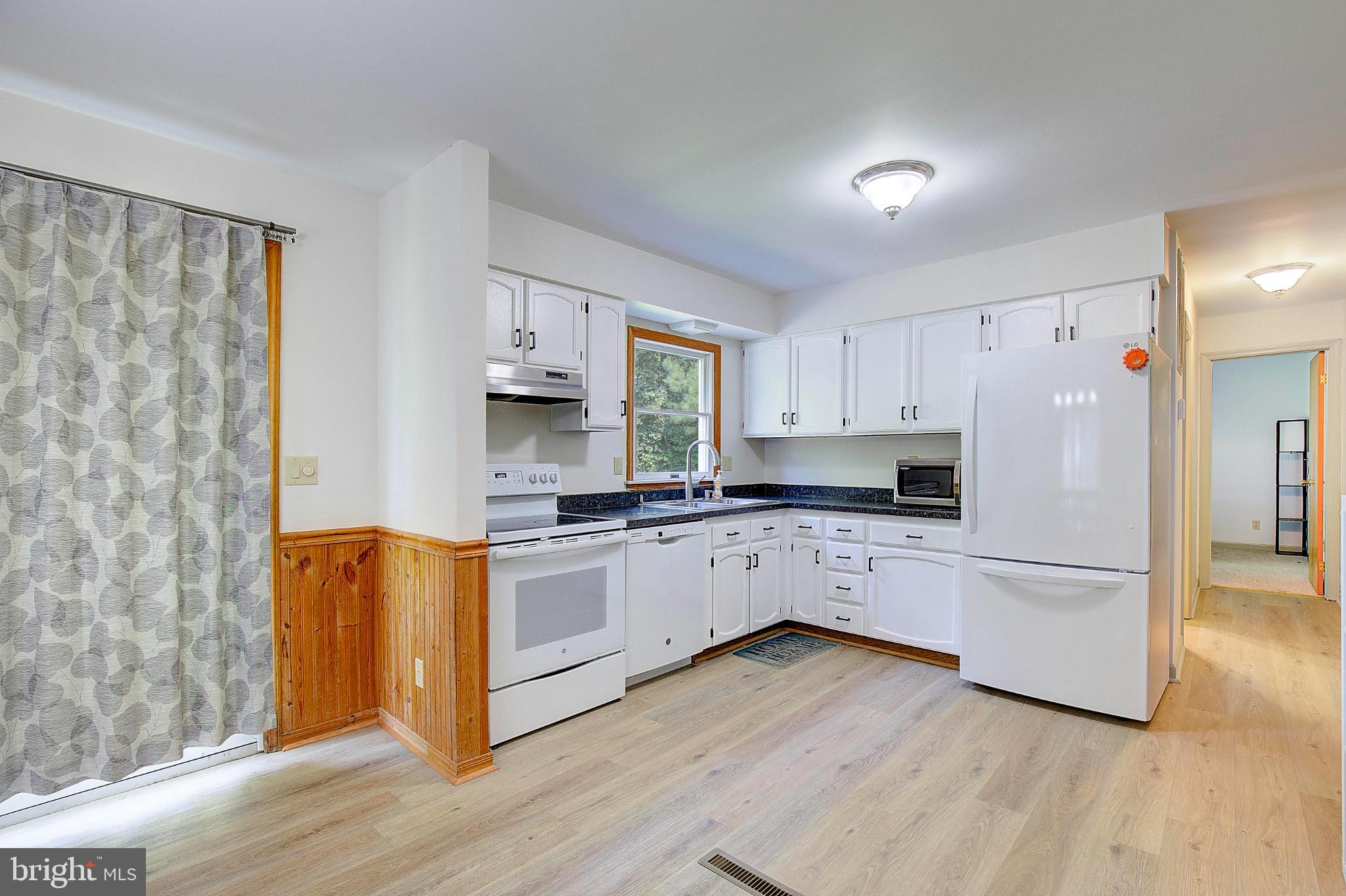 49220 Demko Road Lexington Park, MD 20653 - Photo 16 of 48 a kitchen with stainless steel appliances granite countertop a refrigerator a stove a sink and white cabinets with wooden floor
