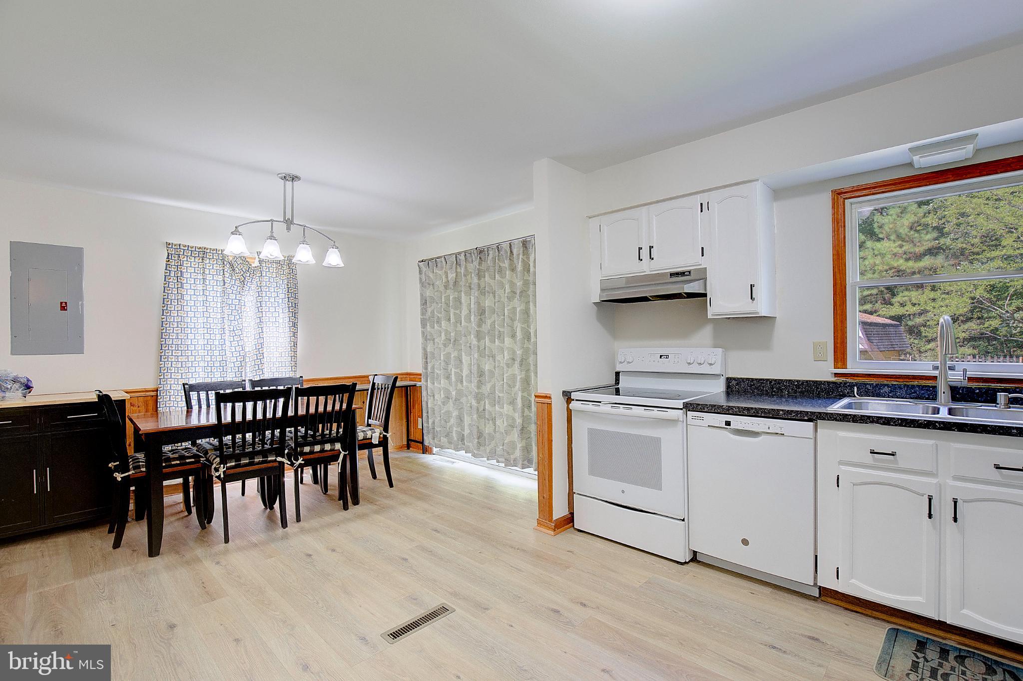 49220 Demko Road Lexington Park, MD 20653 - Photo 19 of 48 a kitchen with stainless steel appliances granite countertop a stove a sink dishwasher a dining table and chairs with wooden floor