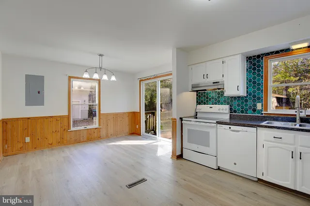 a large white kitchen with granite countertop a large window and a white counter top