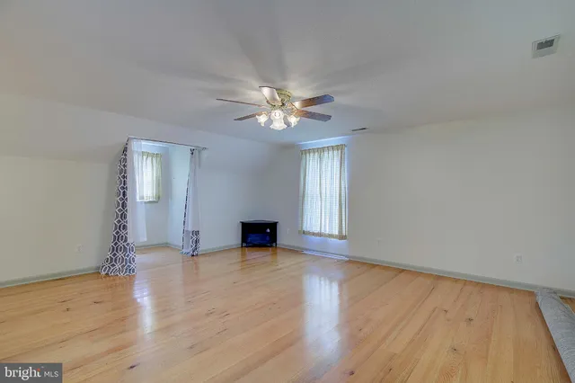 a view of an empty room with window and wooden floor