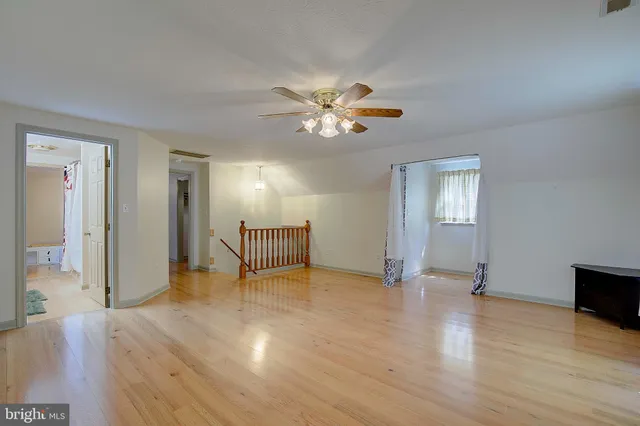 an empty room with wooden floor and ceiling fan