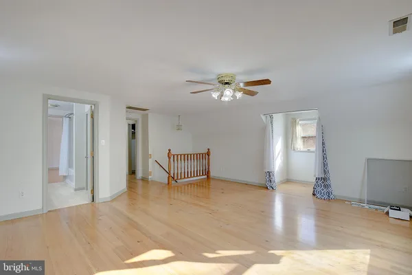 a view of an empty room with window and wooden floor