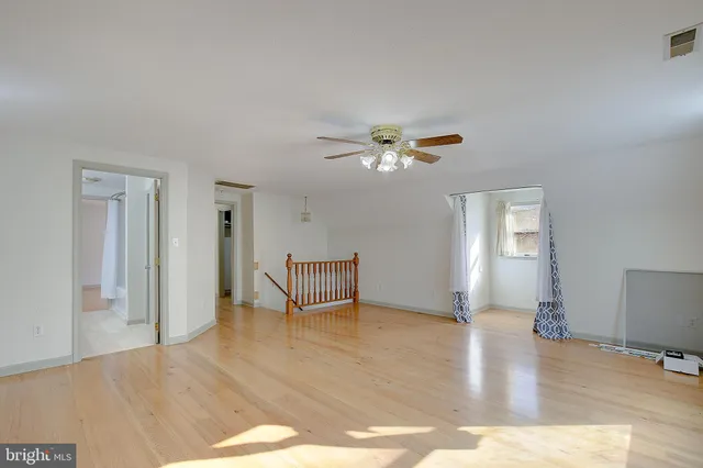 a view of an empty room with window and wooden floor