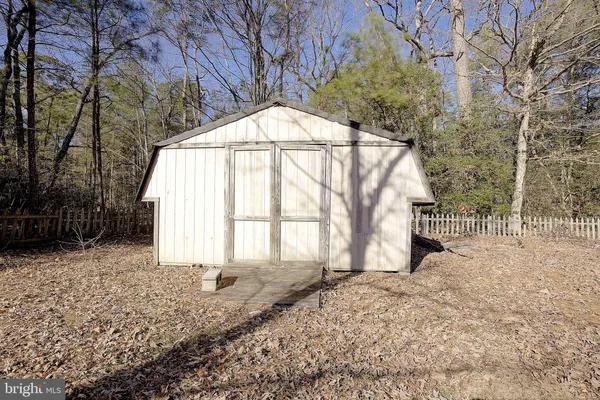 a view of a house with wooden fence and large trees