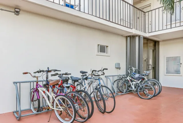 a front view of a multi story building with yard and trees