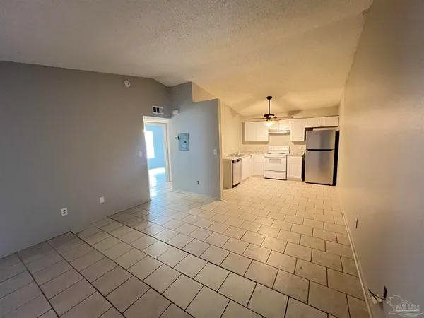 a view of a refrigerator in kitchen and empty room