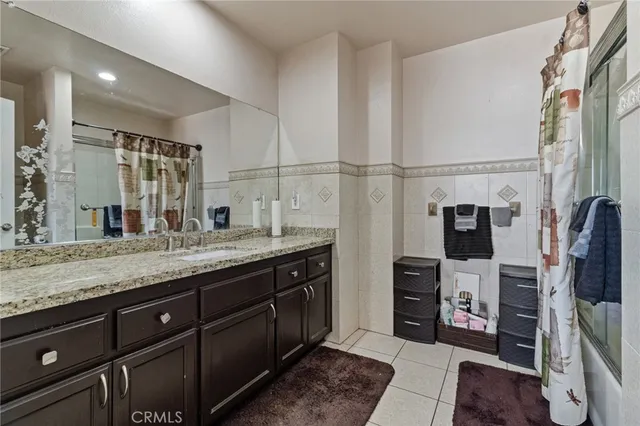 a bathroom with a granite countertop sink a mirror and shower