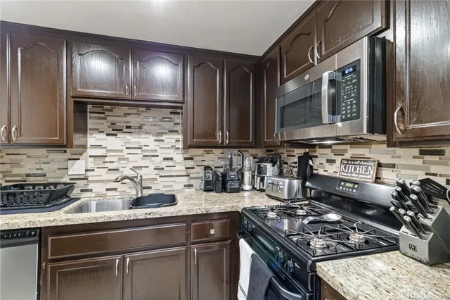 a kitchen with stainless steel appliances granite countertop a stove a sink and a microwave