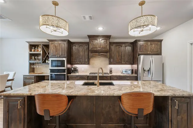 a kitchen with granite countertop a table chairs and a chandelier