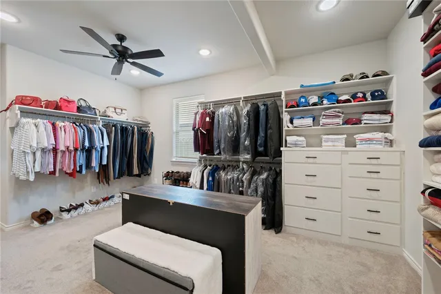 a walk in closet with clothes and shoes