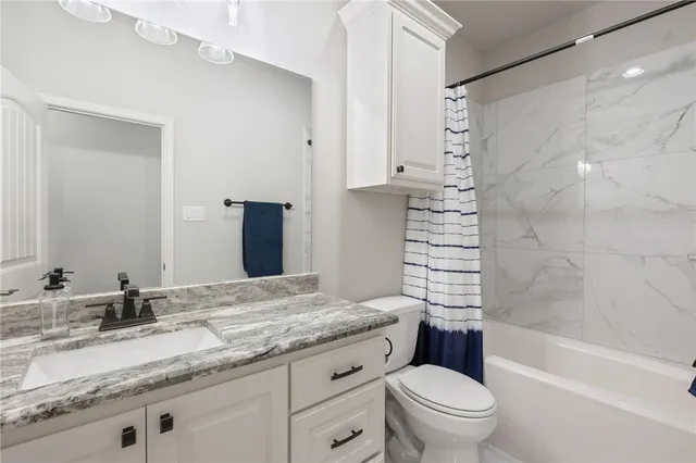 a bathroom with a granite countertop sink a toilet and shower