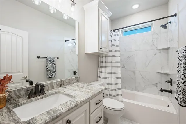 a bathroom with a granite countertop sink a toilet a mirror a shower and a bathtub