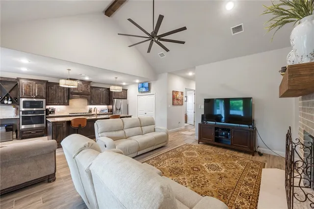 a living room with furniture and a flat screen tv with kitchen view