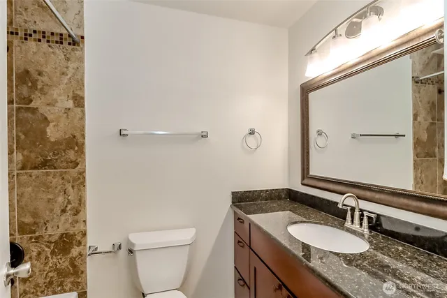 a bathroom with a granite countertop sink toilet a mirror and shower