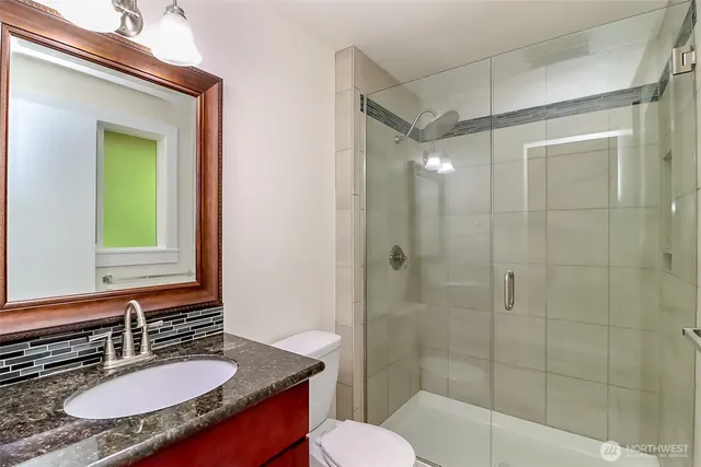 a bathroom with a granite countertop sink toilet a mirror and shower