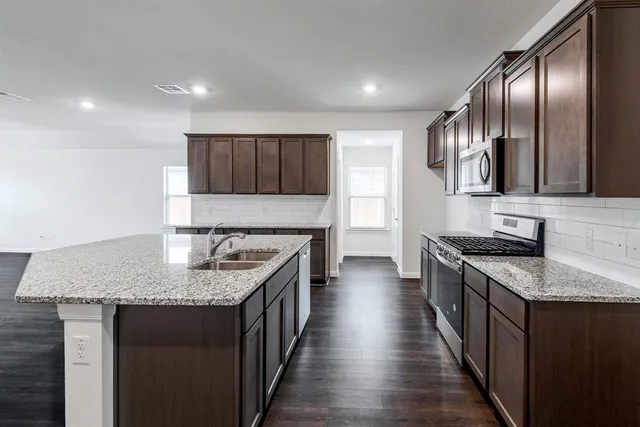 a kitchen with stainless steel appliances granite countertop a sink stove and refrigerator