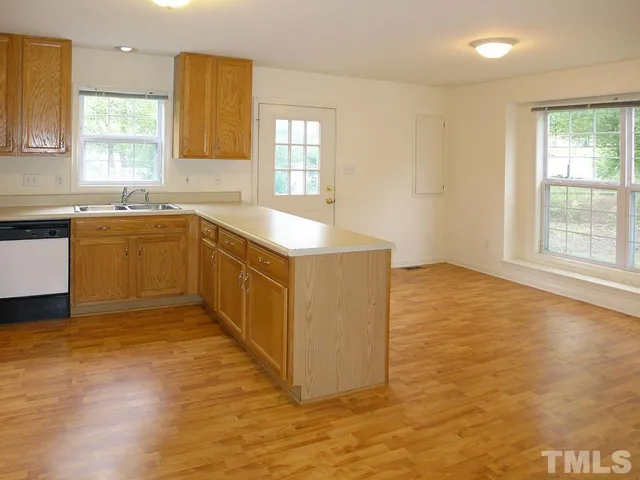 a view of a kitchen with kitchen island a sink wooden floor and a large window