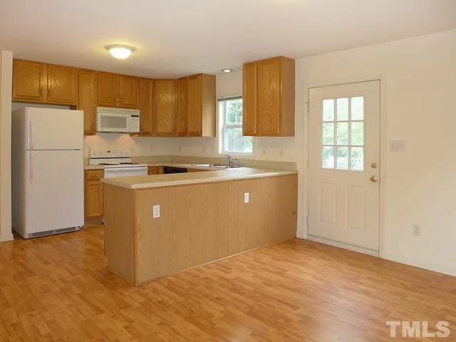 a kitchen with stainless steel appliances granite countertop a stove a sink a refrigerator white cabinets and wooden floor