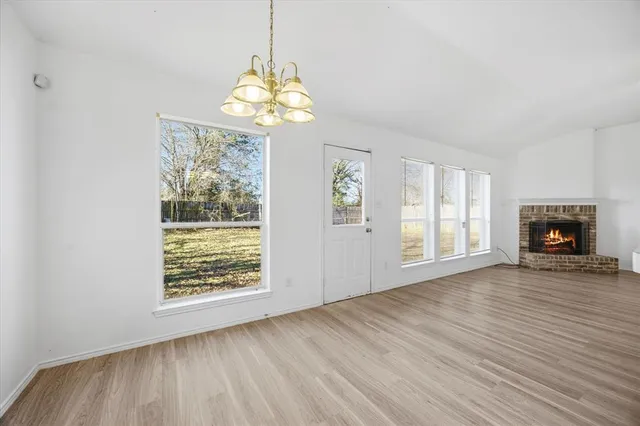 an empty room with wooden floor chandelier and windows