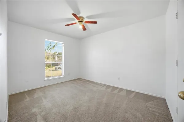 an empty room with windows and fan view