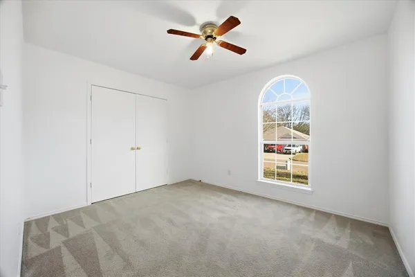 an empty room with windows and ceiling fan